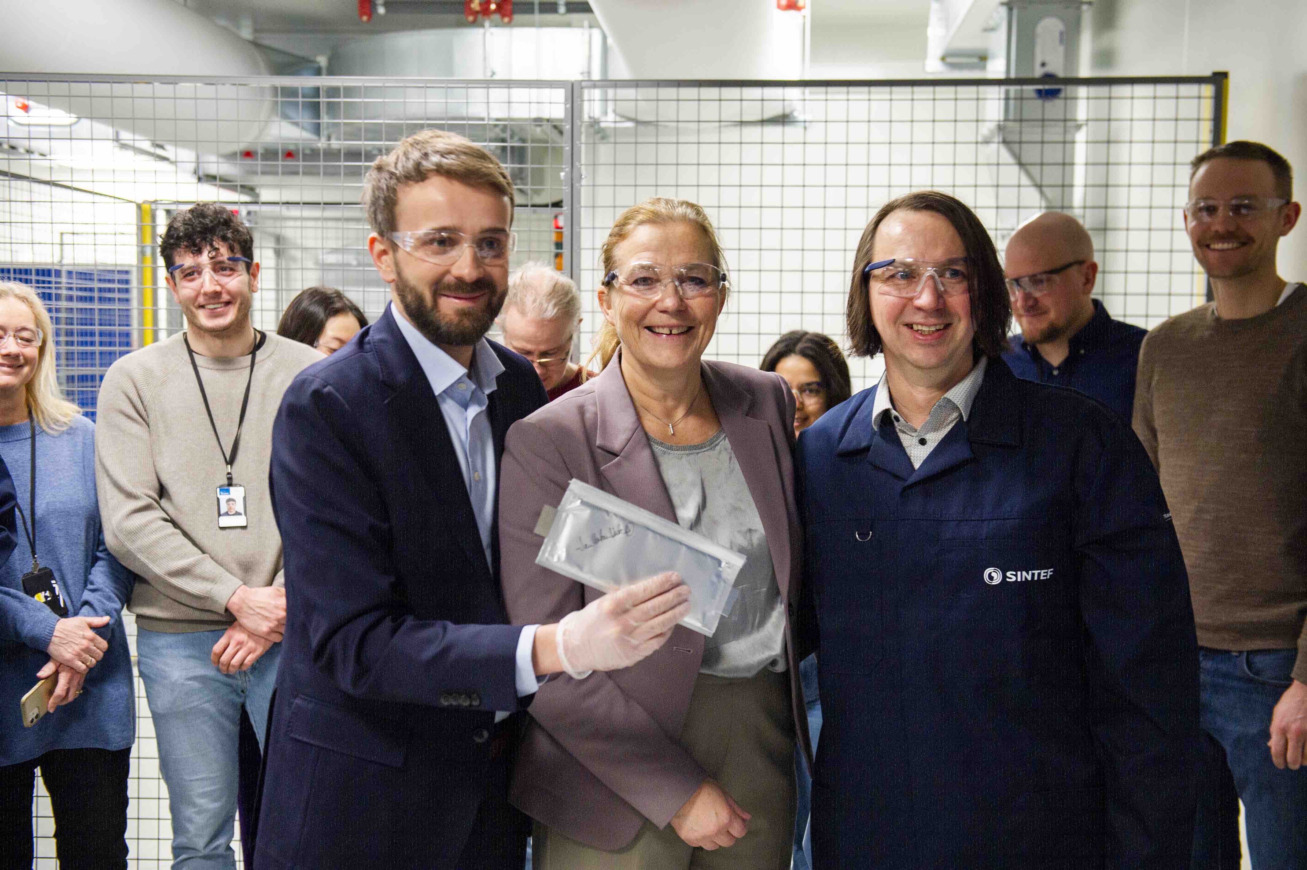 Næringsminister Jan Christian Vestre feirer produksjonen av den første battericellen noensinne i SINTEF Battery Lab sammen med SINTEFs konsernsjef Alexandra Bech Gjørv og seniorforsker Paul Inge Dahl. Foto: SINTEF/Karoline Ravndal Lorentzen